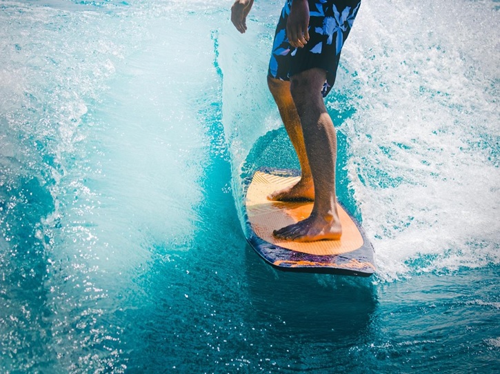 A close up of a man’s legs as he surfs